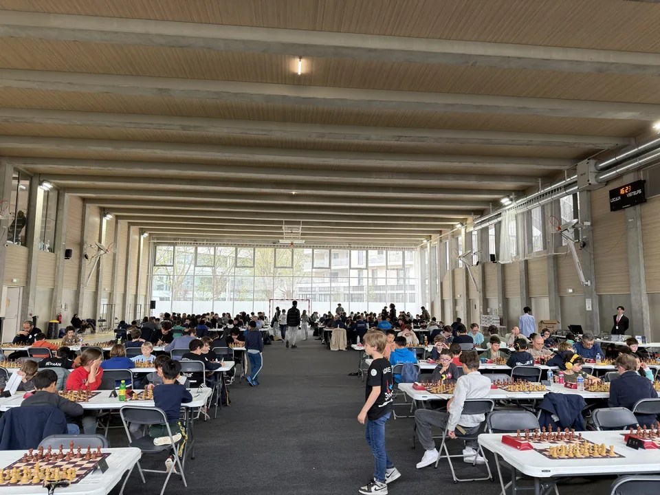 Vue de la salle et des joueurs autour des échiquiers.